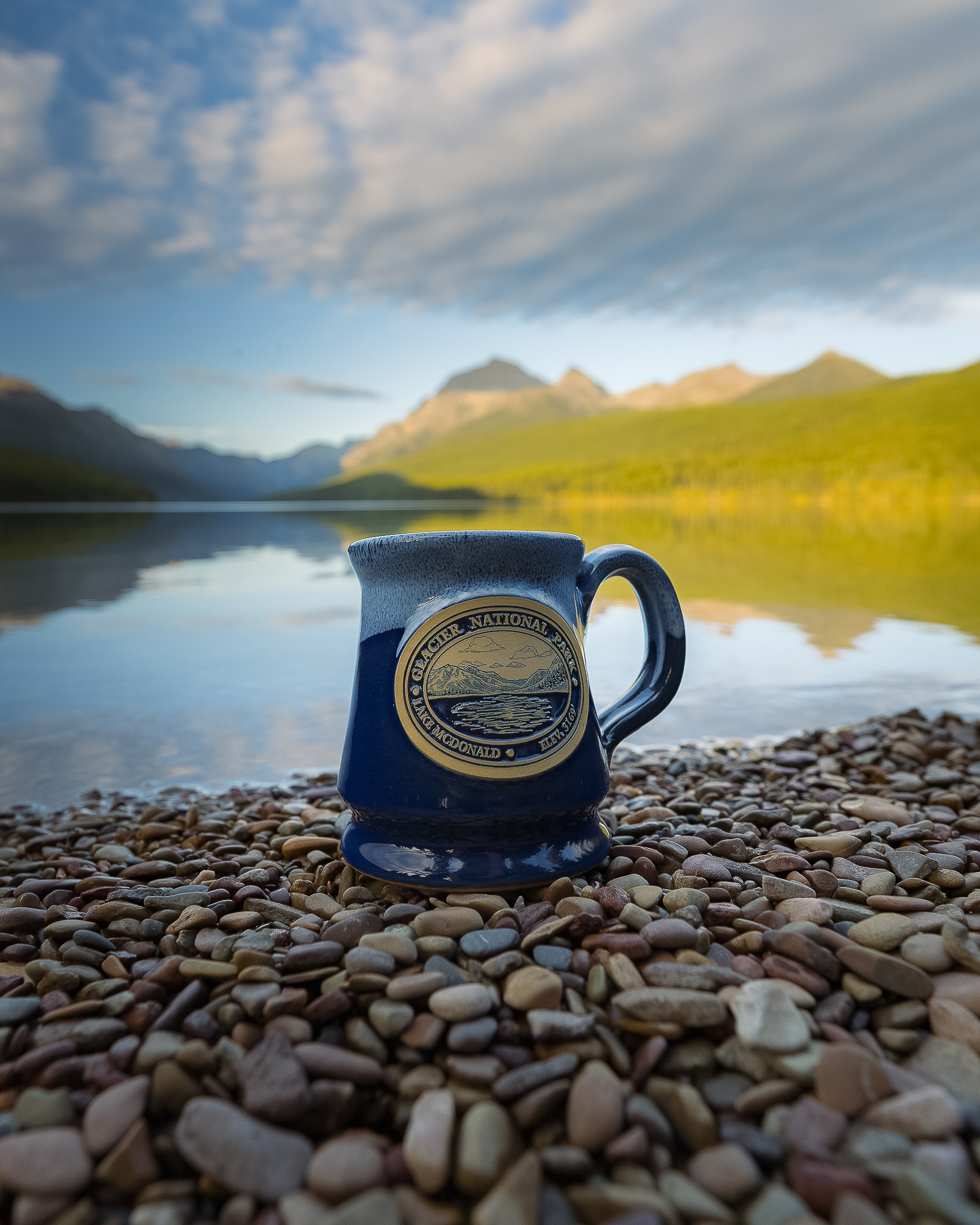 glacier mugs on the bank of a lake with the view of the glacier mountains in the back